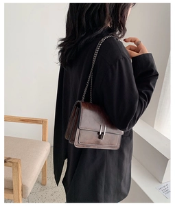 Détail d'un sac bandoulière marron vintage avec chaîne et surpiqûres sur un mannequin