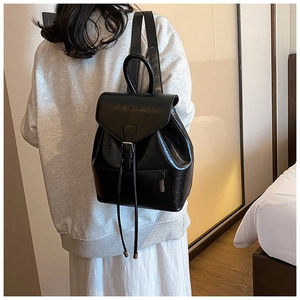 Détail d'un sac à dos en cuir noir brillant avec boucle en métal et cordon de serrage