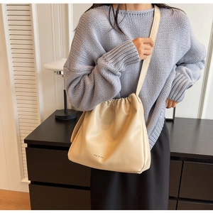 Detail der cremeweißen Falten-Beuteltasche mit miao & she Logo und dünnem Schultergurt