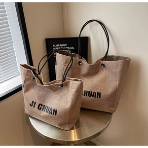 Detail of khaki woven canvas tote bags in two sizes with black rope handles
