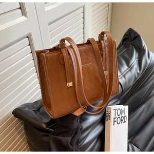Detail of a brown quilted tote bag with golden metal hardware and fashion text