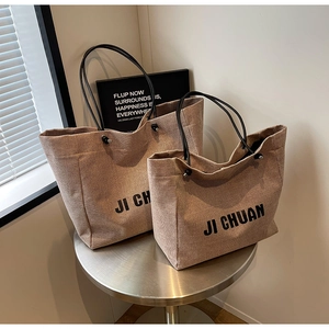 Detailed comparison of large and medium khaki canvas tote bags with black leather straps