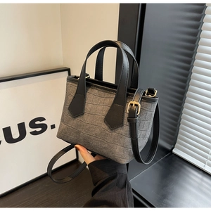 Detail of grey crocodile embossed bucket bag with black handles and gold hardware