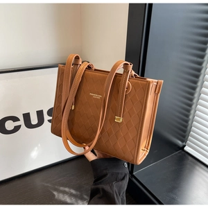 Detailed view of brown quilted tote bag with gold metal hardware and embossed texture