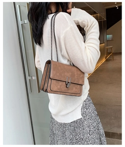 Sac bandoulière en cuir marron vintage avec chaîne en métal porté par un mannequin ici