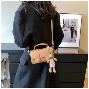 Brown leather crossbody bag with golden twist lock and a cute plush bunny charm