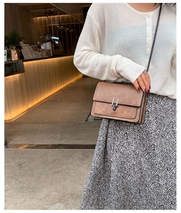 Gros plan d'un sac bandoulière en similicuir marron avec boucle vintage et chaîne