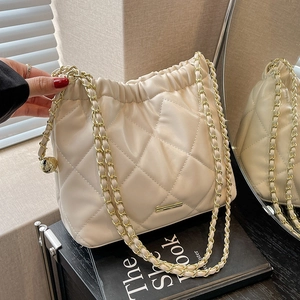 Elegant cream quilted chain bucket bag with gold accents and stylish drawstring design