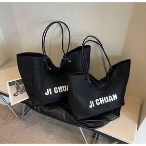 Detail view of large and small black canvas tote bags with white JI CHUAN lettering