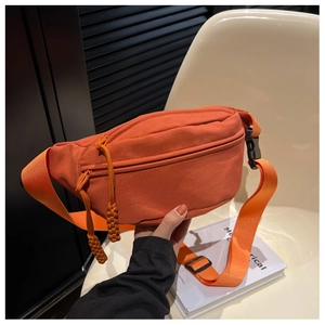 Detail of orange canvas chest bag featuring adjustable strap and buckle closure