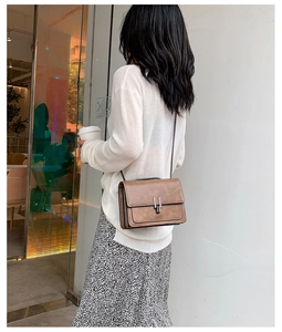 Sac bandoulière vintage marron avec boucle en métal et chaîne porté par un mannequin