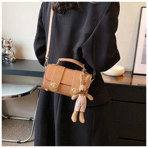 Detail of camel brown crossbody bag with gold clasps and cute plush rabbit charm