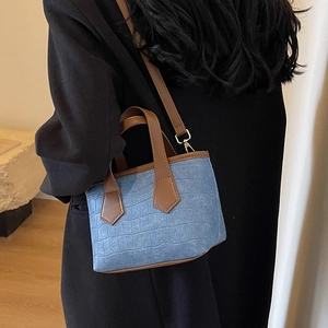 Blue crocodile pattern denim bucket bag with brown leather straps and gold hardware