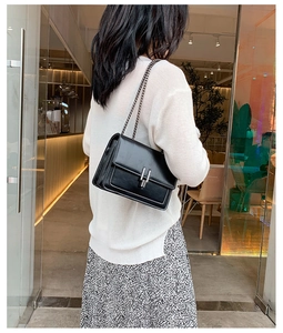 Détail du sac bandoulière en cuir noir avec chaîne argentée et boucle en métal chromé