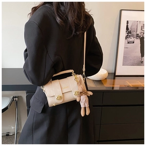 Close-up of beige crossbody bag featuring golden hardware and a cute rabbit charm