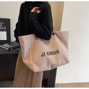 Detail shot of a beige woven tote bag with JI CHUAN text and large capacity for commuting