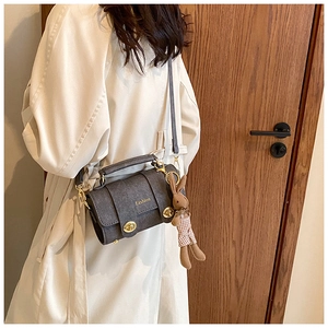 Detail of dark grey retro crossbody bag with gold buckle and plush rabbit charm