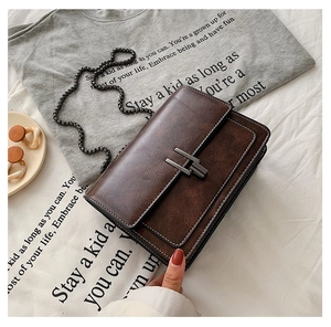 Détail de la besace en cuir PU marron avec coutures blanches et bandoulière chaîne