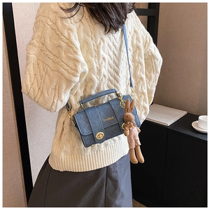 Detail of navy blue crossbody bag with golden lock and plush bunny charm