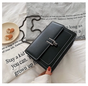Détail du sac bandoulière noir avec surpiqûres blanches et bandoulière chaîne argent