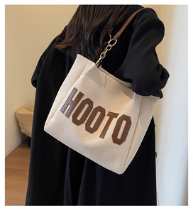 Detail of off-white corduroy tote bag with brown leather strap and gold chain