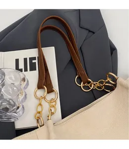 Detail of beige corduroy tote bag with brown leather strap and gold metal hardware