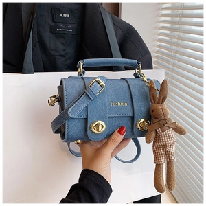 Blue textured crossbody bag featuring golden hardware and a cute knit rabbit charm