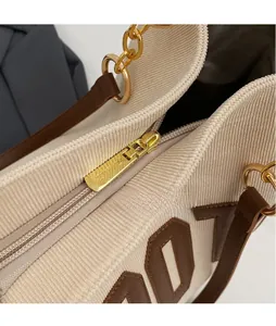 Macro shot of golden metal zipper pull and textured corduroy fabric on a tote bag