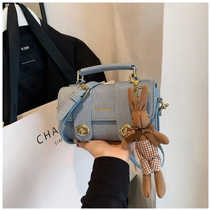Light blue textured crossbody bag featuring a gold clasp and cute rabbit plush charm