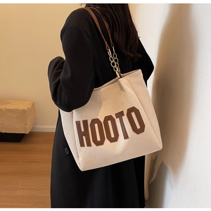 Close-up of the beige canvas tote bag with HOOTO leather logo and chain strap