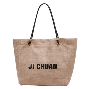 Brown woven tote bag with JI CHUAN logo lettering and black rope handles on white backdrop