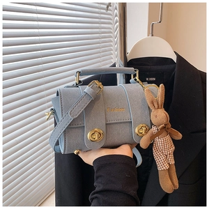 Detail of light blue crossbody bag with gold twist lock and cute bunny pendant