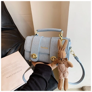 Detail of light blue textured leather handbag with gold clasp and bunny charm