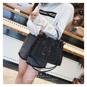 Détail d'un sac en cuir noir avec surpiqûres blanches et boucle argentée iconique