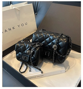 Detail of black quilted leather shoulder bag featuring metal chain and adjustable ball