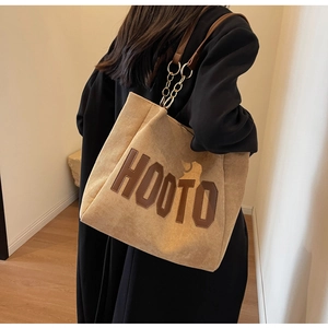 Detail of khaki corduroy tote bag with HOOTO lettering and gold chain leather strap