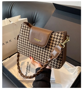 Close-up of retro houndstooth fabric texture and dark brown leather flap on a handbag