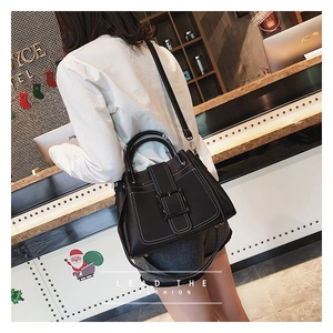 Vue détaillée du sac noir avec coutures contrastées blanches et boucle carrée décorative
