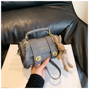 Detail of grey tweed handbag featuring gold twist lock and cute bunny doll accessory
