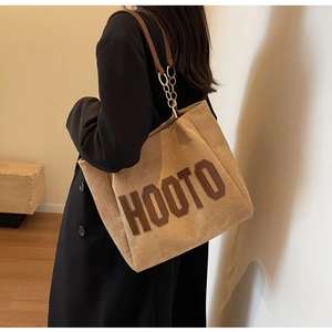 Detail of khaki corduroy tote bag featuring brown HOOTO embroidery and chain straps