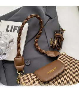 Close-up of houndstooth wool fabric texture and brown leather strap on bag