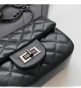 Close-up detail of black quilted leather bag featuring silver twist lock and metal chain strap