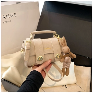 Detail of beige square handbag with gold Fashion logo and cute bunny plush charm