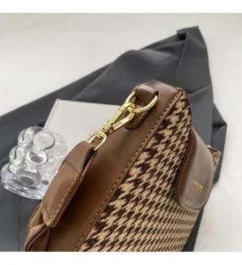 Detail of vintage houndstooth bag with brown leather trim and golden metal clasp