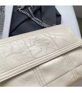 Close-up of beige quilted bag showing soft leather texture and silver chain strap details