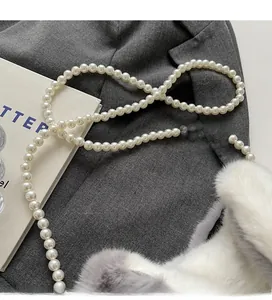 Detail of soft faux fur texture and elegant pearl strap on the plush bucket bag