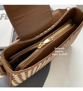 Close-up of smooth gold-tone zipper on retro woven shoulder bag with leather trim