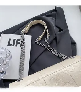 Detail of beige quilted shoulder bag with silver chain strap and leather padding