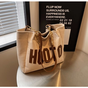 Detailed shot of beige corduroy tote with brown leather HOTO patch and chain strap