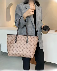 Large tote bag with brown pattern worn over a grey plaid blazer for daily commute